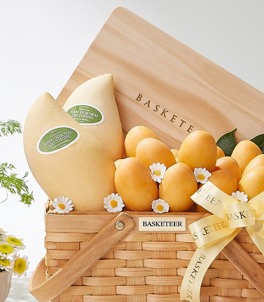 Woven wood gift basket with premium Nam Dok Mai mangoes, orange Thai fruit, and white daisies