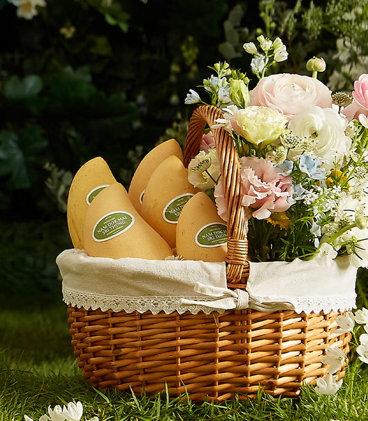 Luxury wicker basket with Thai Nam Dok Mai mangoes, mixed fresh flowers, and white lace lining for premium gifting