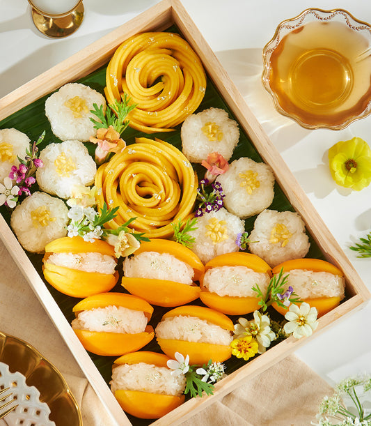 Premium mango sticky rice gift box with edible gold leaf, fresh tropical fruits, and artisan Thai desserts on wooden tray
