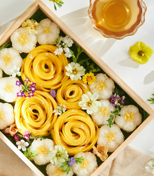 Luxury golden mango sticky rice gift box with edible silver leaf, fresh flowers, and sticky rice portions on banana leaves