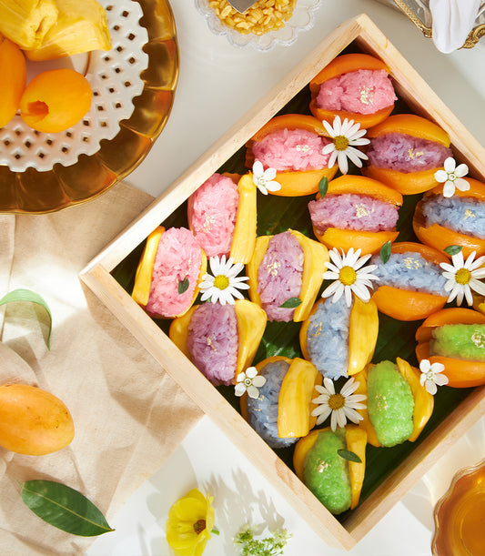 Colorful Thai sticky rice with mango and jackfruit, topped with edible gold and fresh tropical fruit garnish