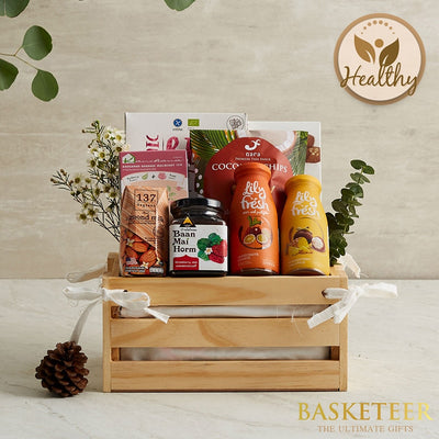 Wooden craft crate filled with almond milk, strawberry jam, coconut chips, and fruit juices, tied with white ribbons and