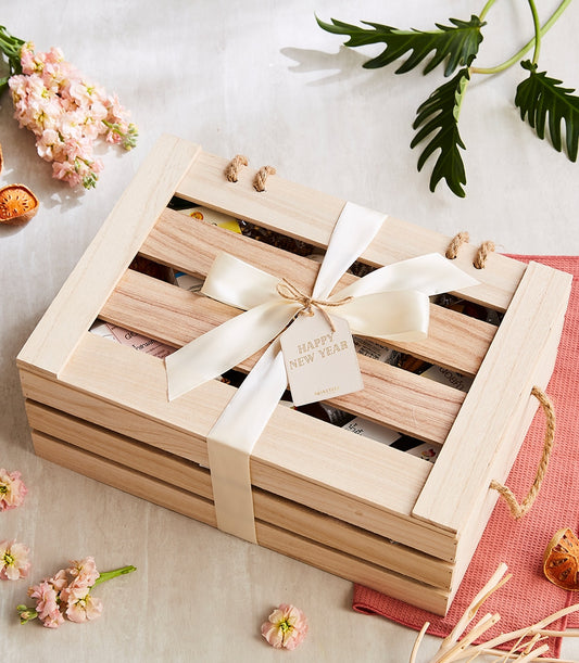 Wooden gift crate with satin ribbon, fresh flowers, and dried citrus in natural artisan presentation
