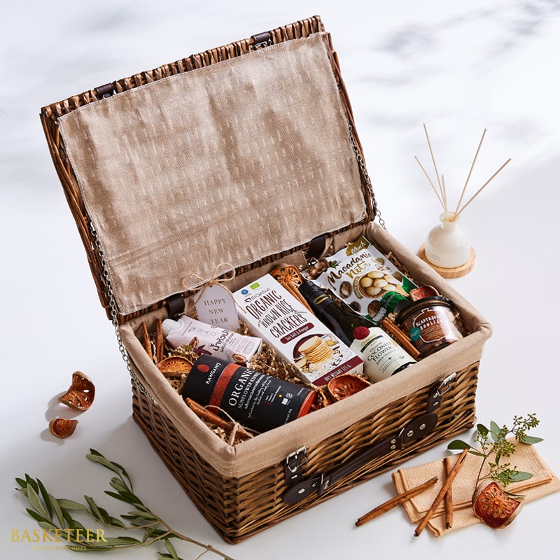 Wicker picnic hamper filled with gourmet snacks, organic spreads, and wellness items with ceramic diffuser