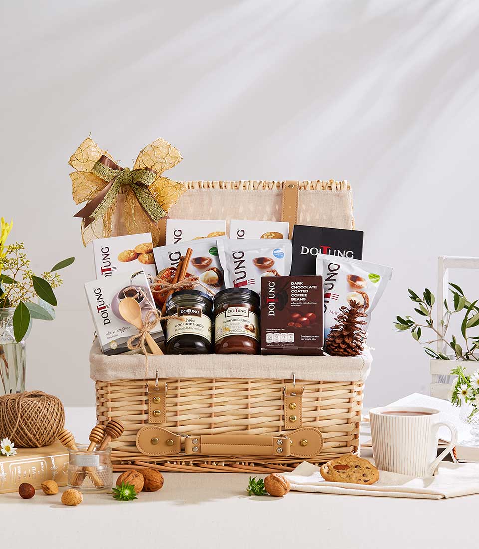 Wicker gift basket filled with Doi Tung gourmet items, honey, chocolate, and wellness products with gold ribbon