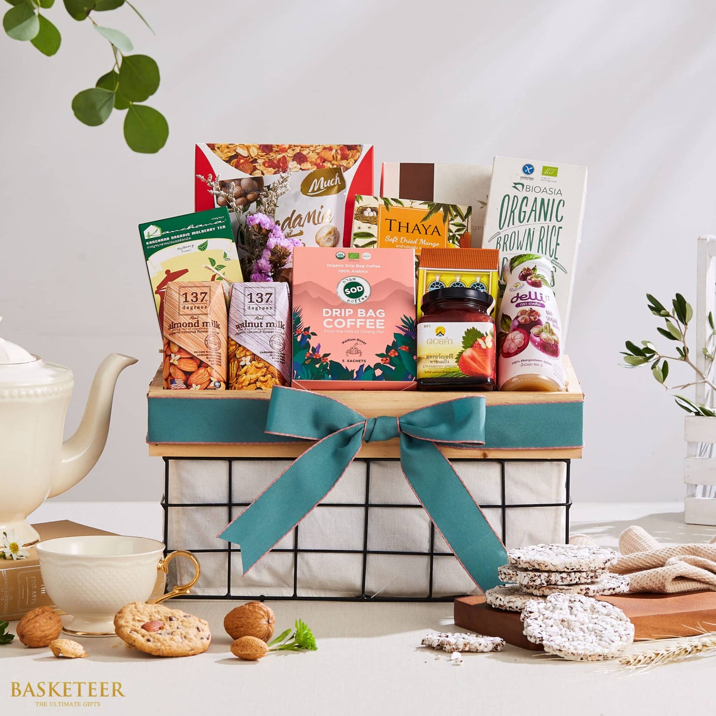 Curated Thai gift basket with organic rice, coffee, dried mango, nuts, and plant-based milk with teal ribbon bow