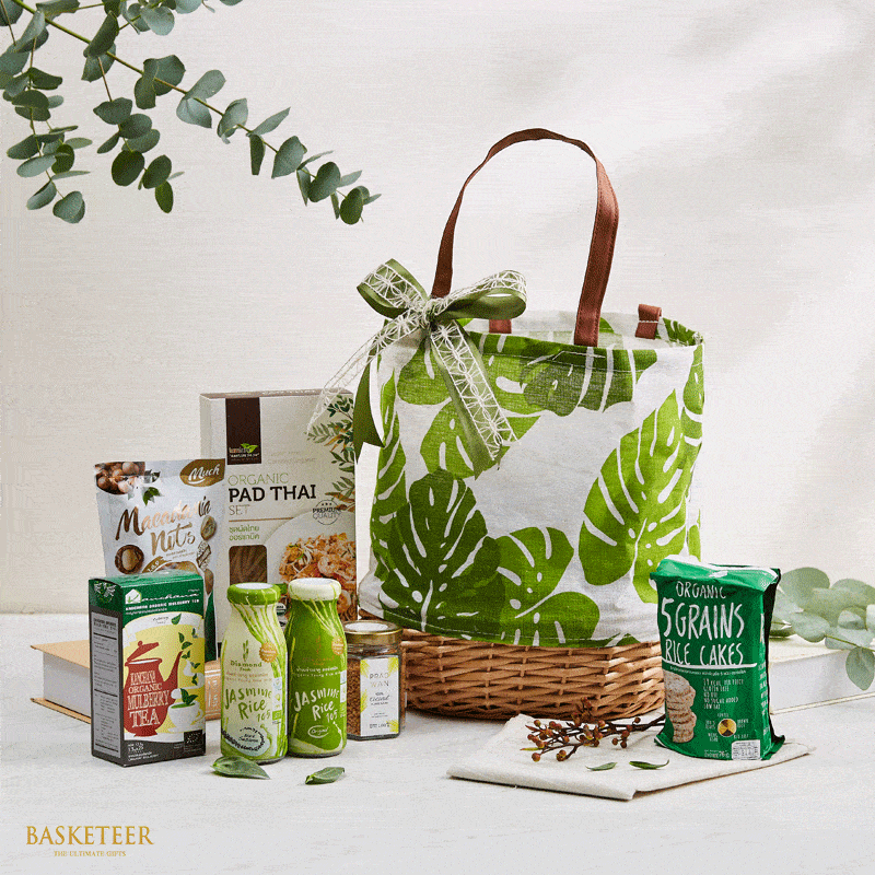 Thai gourmet gift set with macadamia nuts, organic pad thai, mulberry tea, and rice cakes in white leaf-patterned tote bag