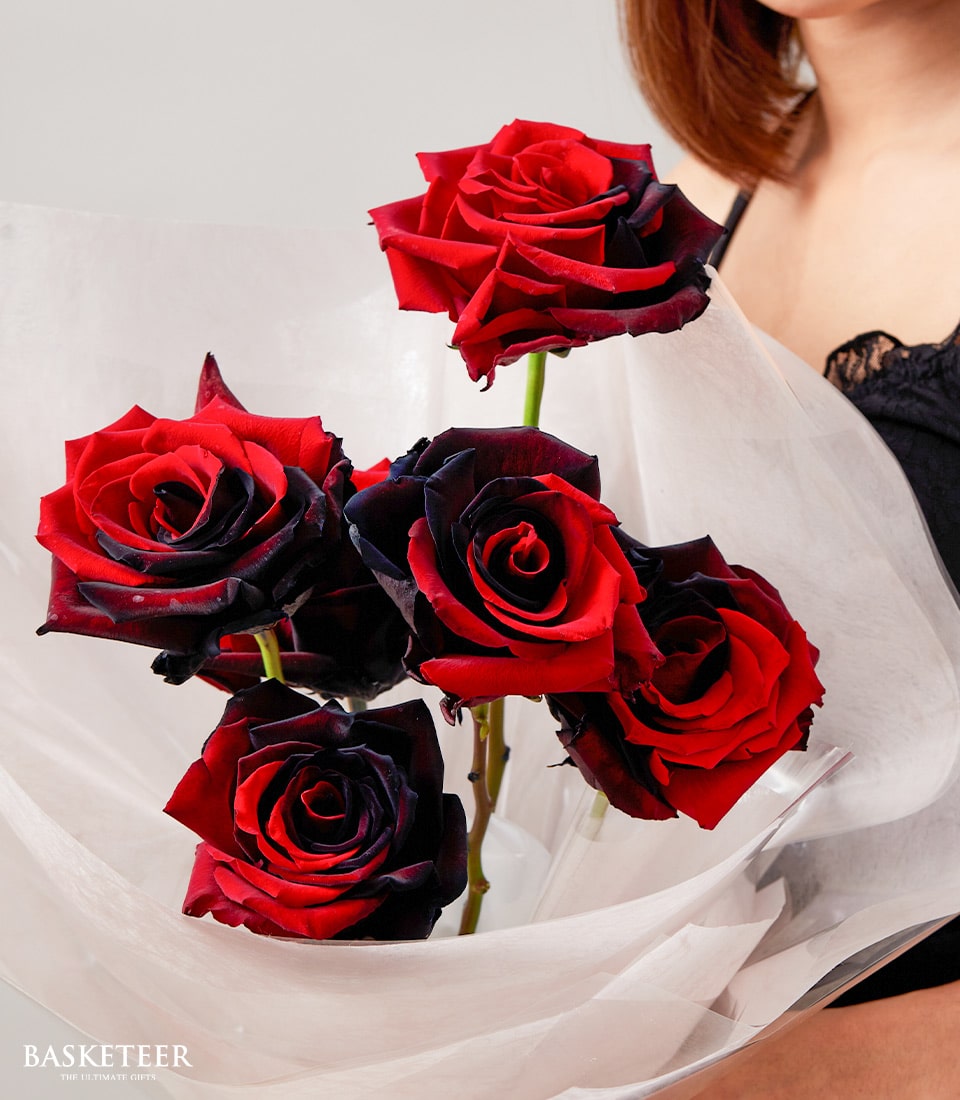 Red and black ombré roses bouquet with dramatic two-toned petals, wrapped in crinkled cellophane for Valentine's Day