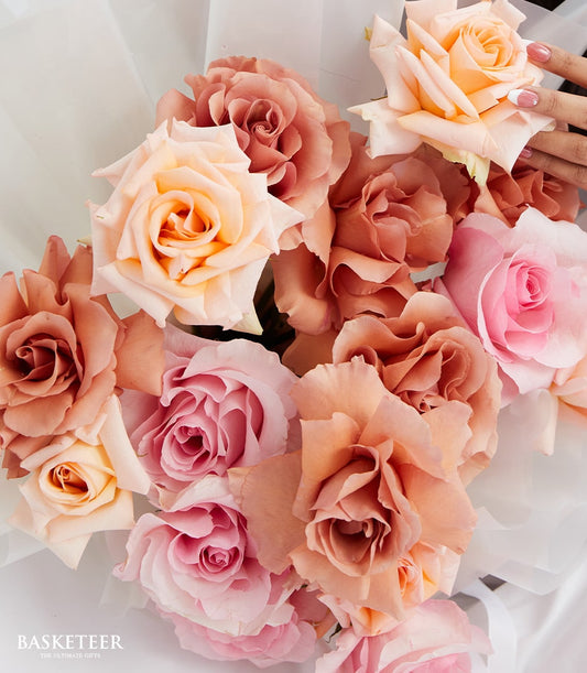 Premium pink and peach rose bouquet wrapped in white paper, held by hand with French manicure