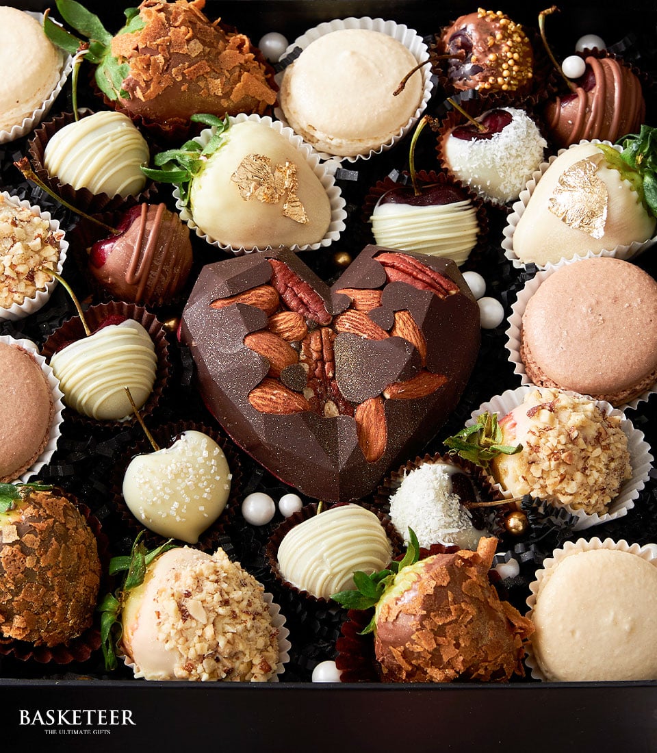 Luxury Valentine gift box with dark chocolate heart, strawberries, macarons, and gold leaf treats