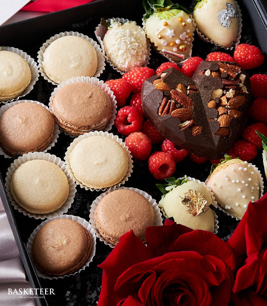 Luxury Valentine's gift box with red roses, chocolate-covered strawberries, macarons, and dark chocolate heart