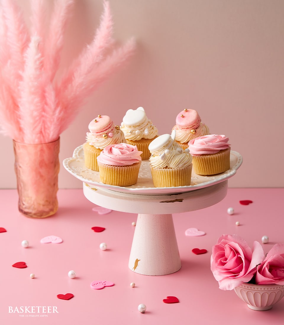 Vanilla cupcakes with rose frosting and macarons on white stand, pink pampas grass bouquet, Valentine's gift set