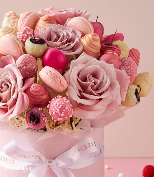 Pink roses, macarons, and chocolate-covered strawberries in luxury Valentine's gift box