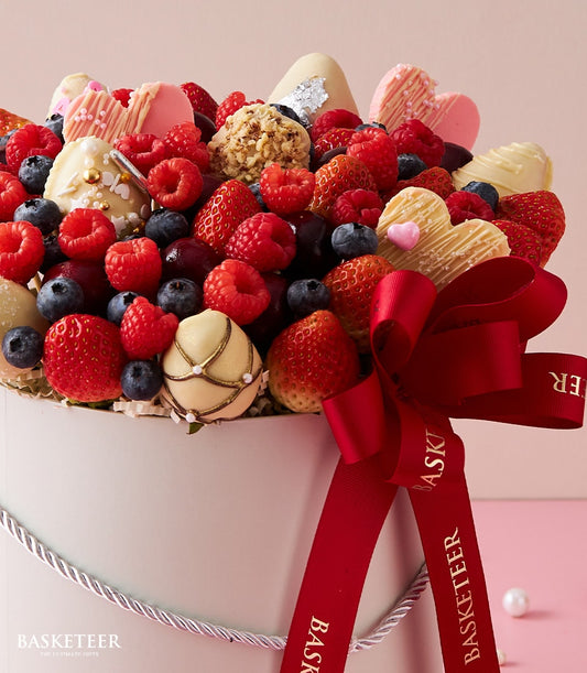 Luxury berry box with chocolate-covered strawberries, raspberries, blueberries, and heart-shaped chocolates in white