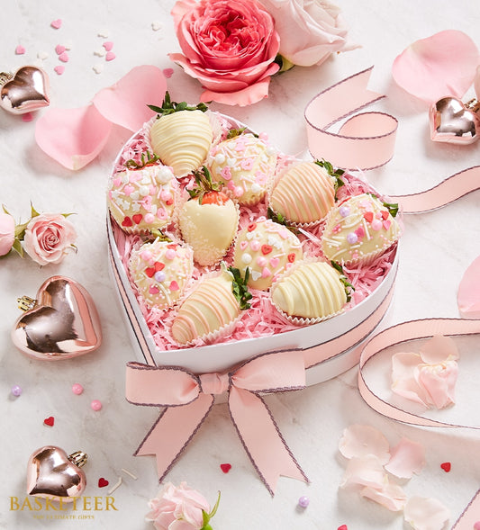 Heart-shaped box of white chocolate-dipped strawberries with pink and red sprinkles, tied with pink ribbon for Valentine's