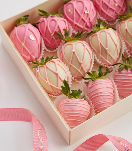 Luxury chocolate-covered strawberries in pink and white with gold accents, arranged in elegant gift box for Valentine's Day