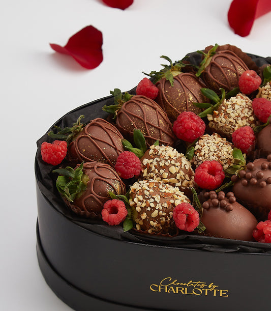 Heart-shaped luxury chocolate box with dark chocolate-covered strawberries, raspberries, and gold-dusted berries for
