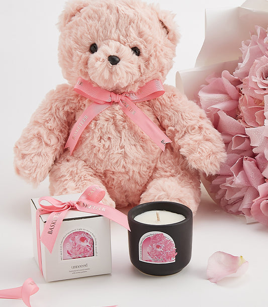 Luxury Valentine's Day gift set with pink teddy bear, rose geranium scented candle, and fresh pink flower bouquet