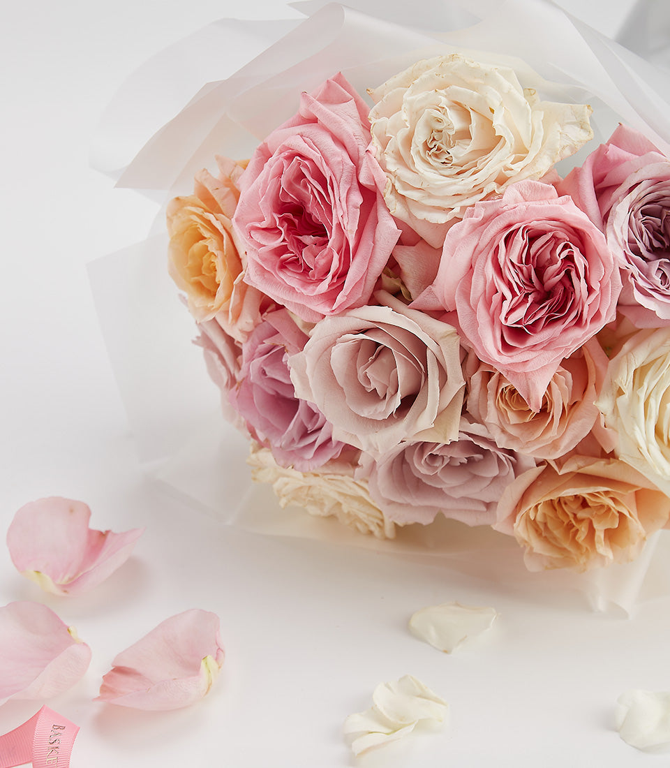 Pastel pink, peach, and cream roses bouquet with white wrapping for anniversaries and Valentine's Day