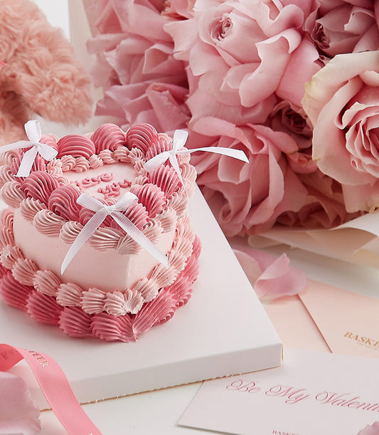 Heart-shaped Valentine's cake with pink roses, petals, and romantic gift set for couples