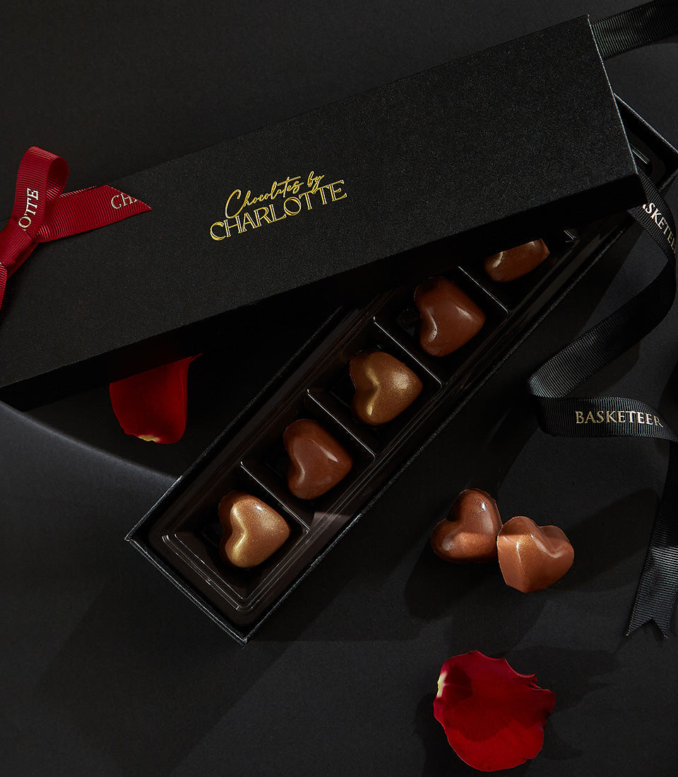 Luxury black gift box of six heart-shaped chocolates with gold trim, tied with red and black ribbons