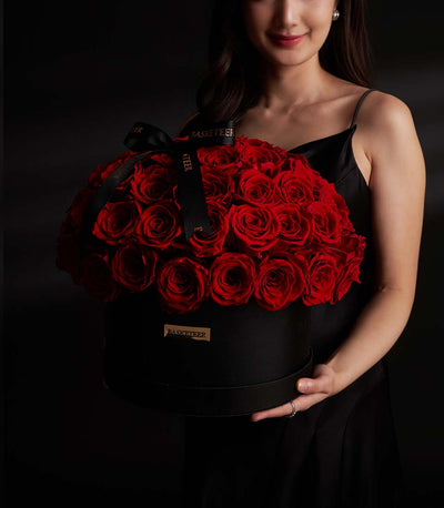 Lush red rose arrangement from Flowers by Basketeer in a black hat box, tied with a logo ribbon. Premium flowers Bangkok for same-day flower delivery.