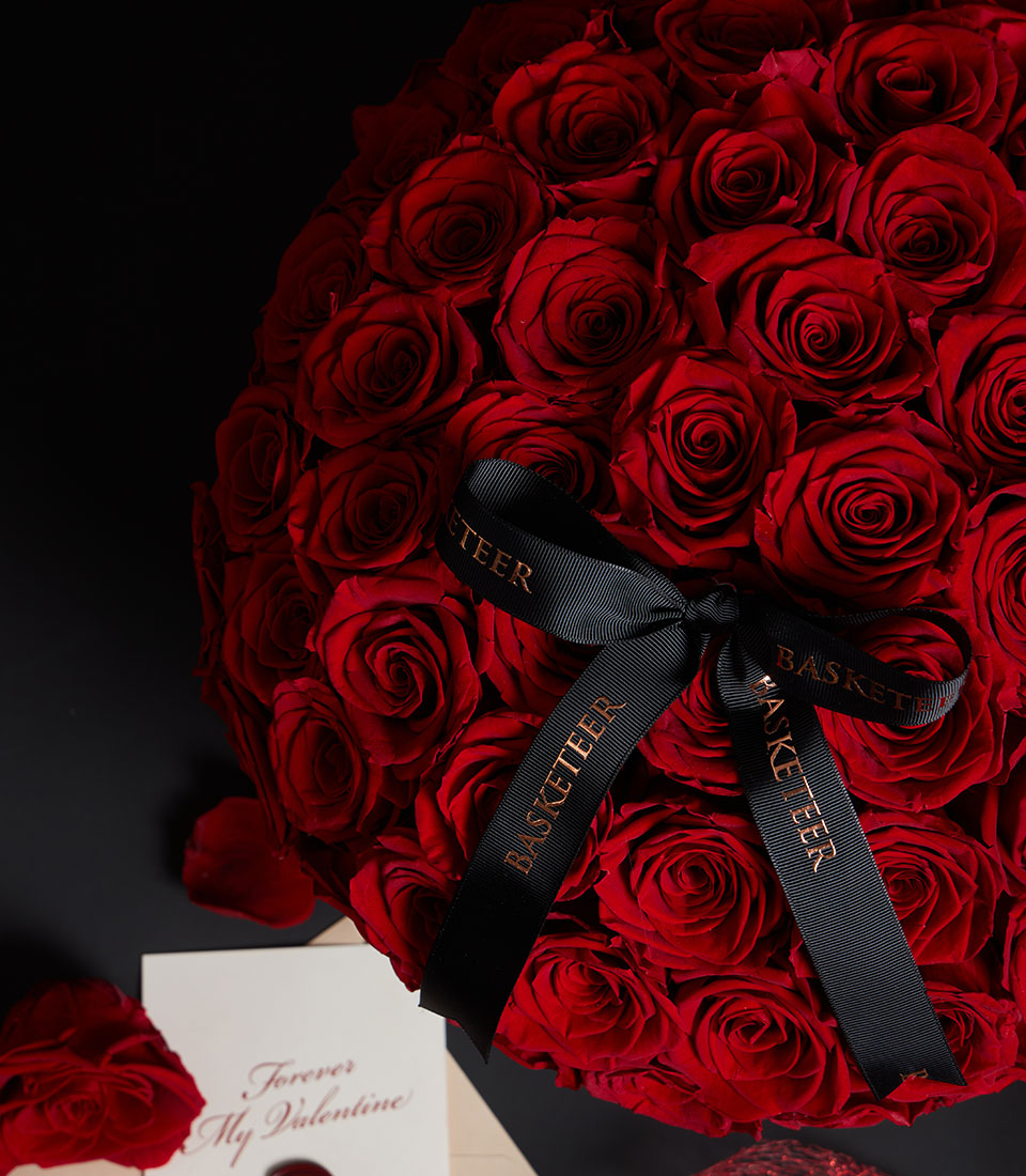 Lush red preserved rose arrangement from Flowers by Basketeer in a hat box, with a branded black ribbon. Premium flower delivery Bangkok.