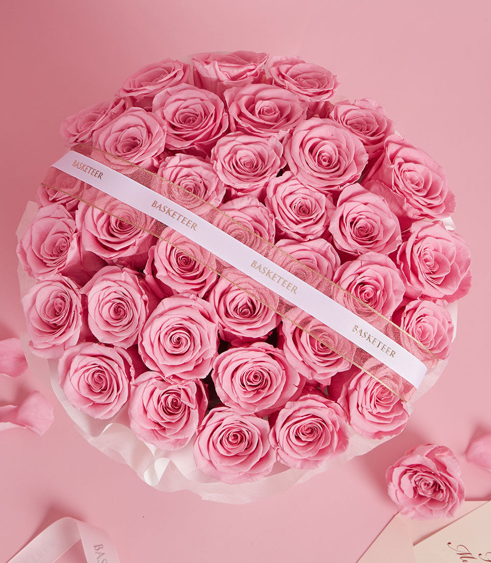 Elegant round arrangement of preserved pink roses in white ruffled box with gold-trimmed ribbon, Valentine's Day luxury gift