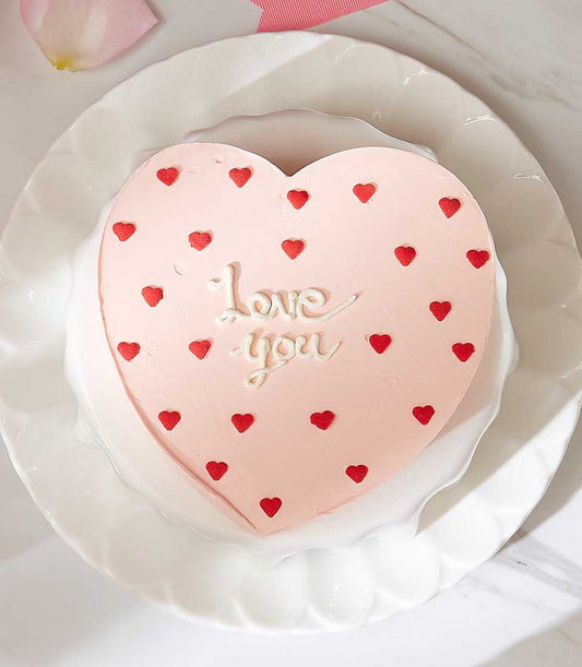 Heart-shaped love cake with pink frosting, red heart sprinkles, and "Love you" message for Valentine's Day
