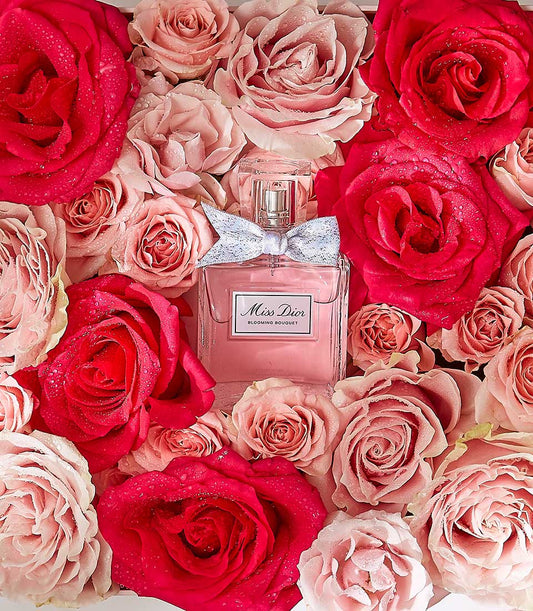 Miss Dior Blooming Bouquet perfume surrounded by fresh red and pink roses with water droplets
