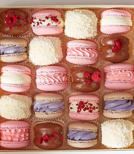 Assorted pastel macarons gift box with raspberry, chocolate, and coconut treats in fluted cups