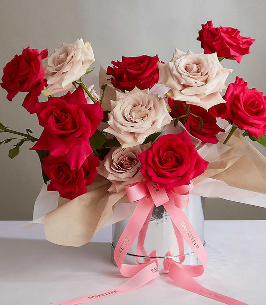 Romantic mix of deep red and blush pink roses in silver cylinder with pink ribbon, anniversary gift