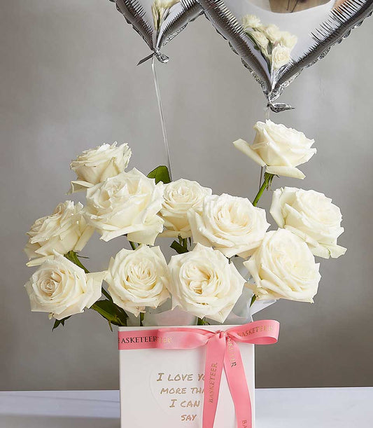 White rose bouquet in luxury gift box with heart balloons and pink ribbon for Valentine's Day