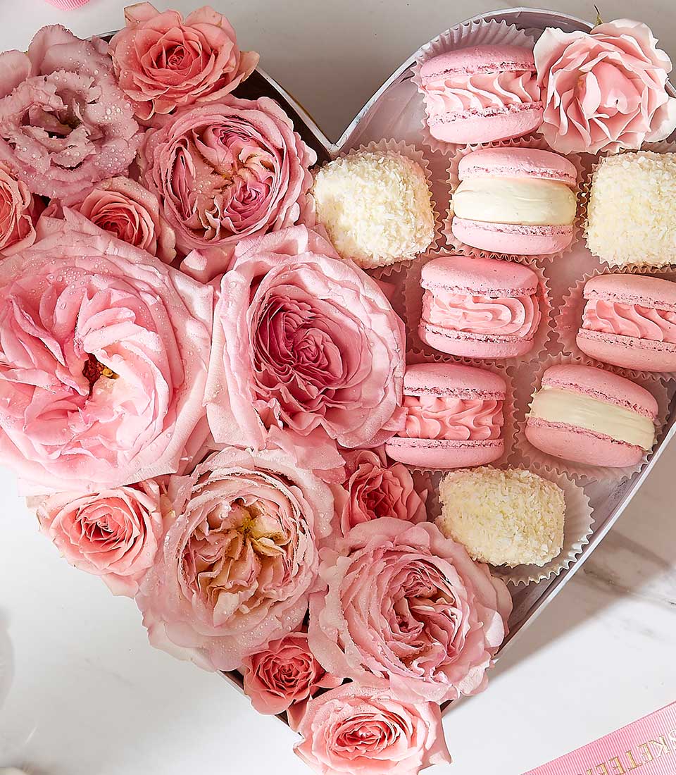 Heart-shaped gift box with fresh pink roses, macarons, and coconut confections for birthdays