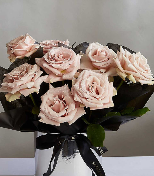 Light pink roses with water droplets in silver vase, black tissue wrap and ribbon
