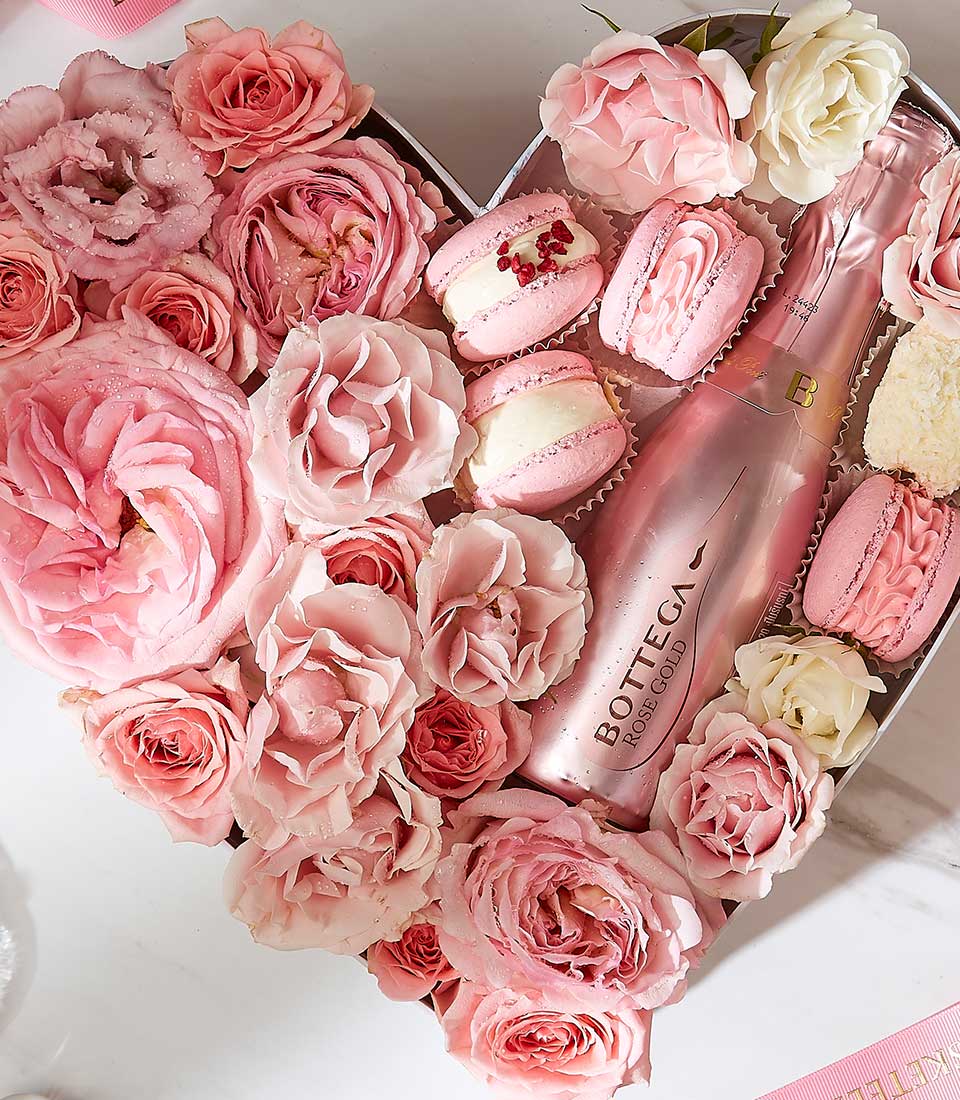 Heart-shaped gift box with pink roses, Bottega rosé sparkling wine, and strawberry macarons for Valentine's Day