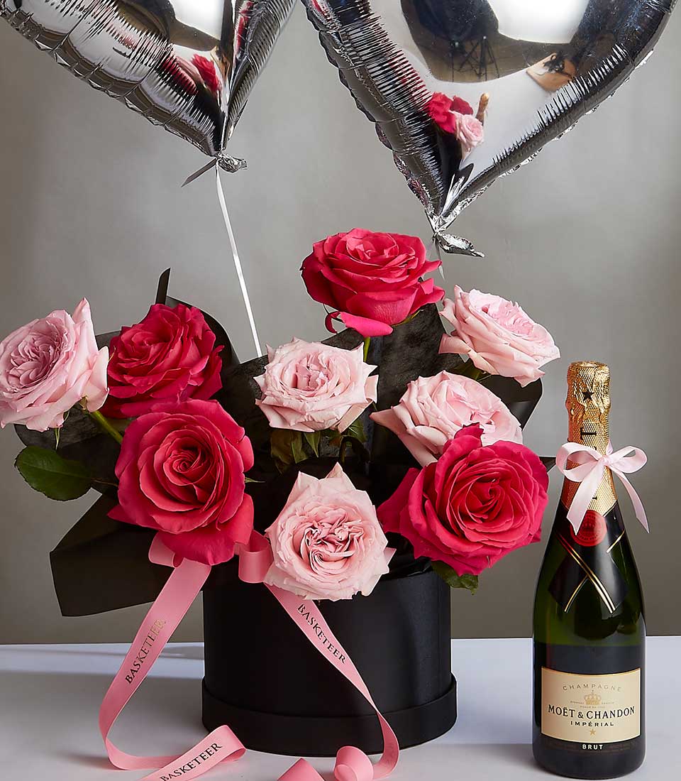 Premium rose arrangement in black hatbox with Moët & Chandon champagne and heart balloons for anniversary celebrations