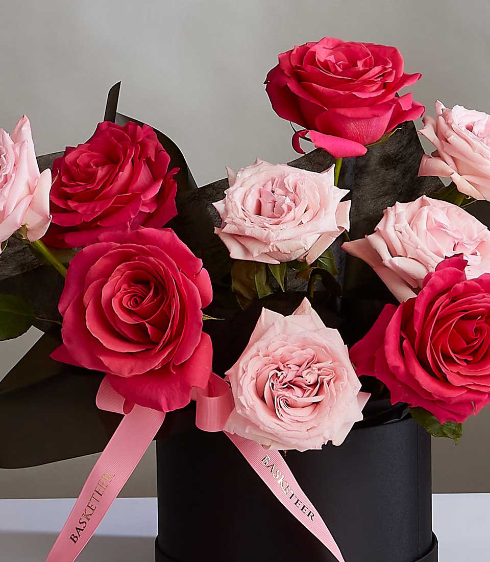 Luxurious midnight pink and fuchsia rose bouquet in black hatbox with gold-ribbon detail