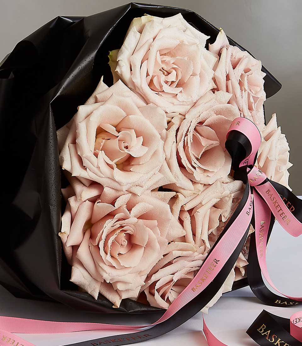 Dewy light pink roses bouquet with black wrap and striped ribbon for Valentine's Day
