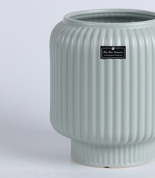 Sage green ceramic vase with vertical ribbed texture and rounded body, ideal for fresh flowers or décor