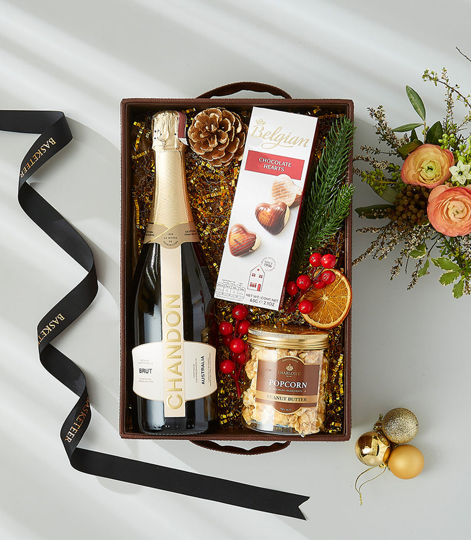 Luxury gift hamper with champagne, heart chocolates, gourmet popcorn, and festive gold accents