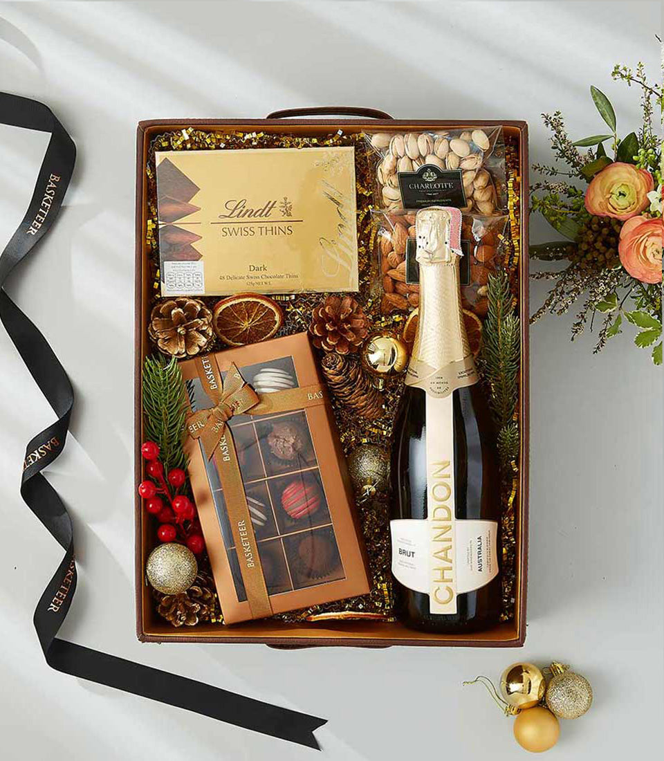 Luxury gift hamper with Chandon sparkling wine, Lindt chocolates, nuts, and festive gold holiday decorations