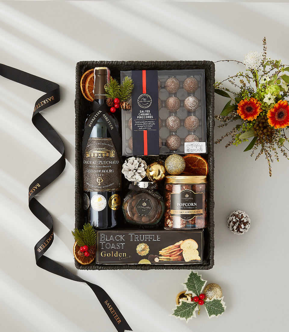 Premium wine gift basket with Chateau Peychaud red wine, gourmet chocolates, and festive holiday florals