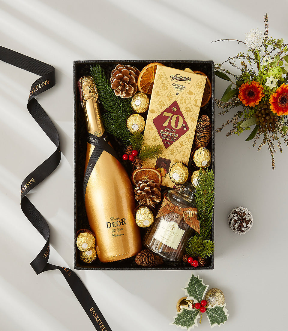 Luxe wine and chocolate gift box with Deor sparkling gold bottle, gourmet chocolates, and festive holiday decorations
