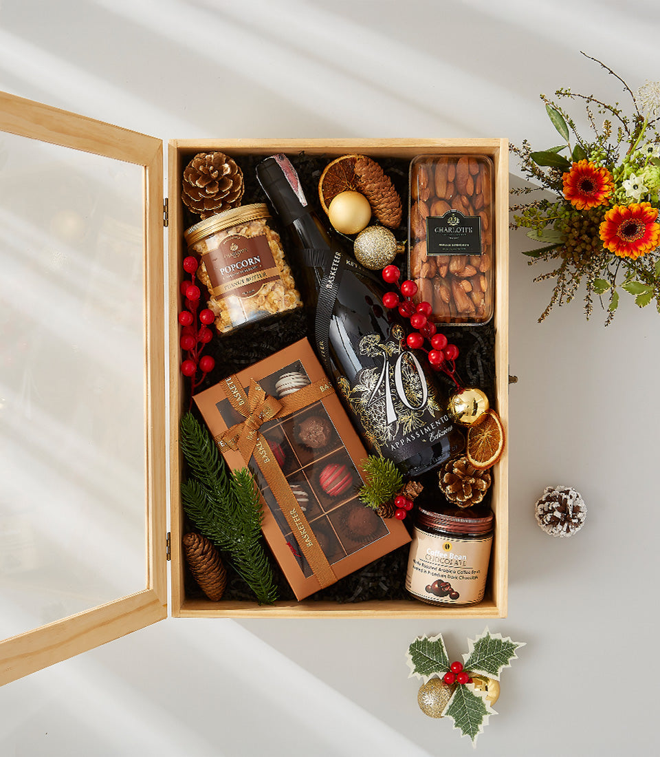 Appassimento red wine gift box with gourmet popcorn, almonds, chocolates, and festive holiday decorations in wooden
