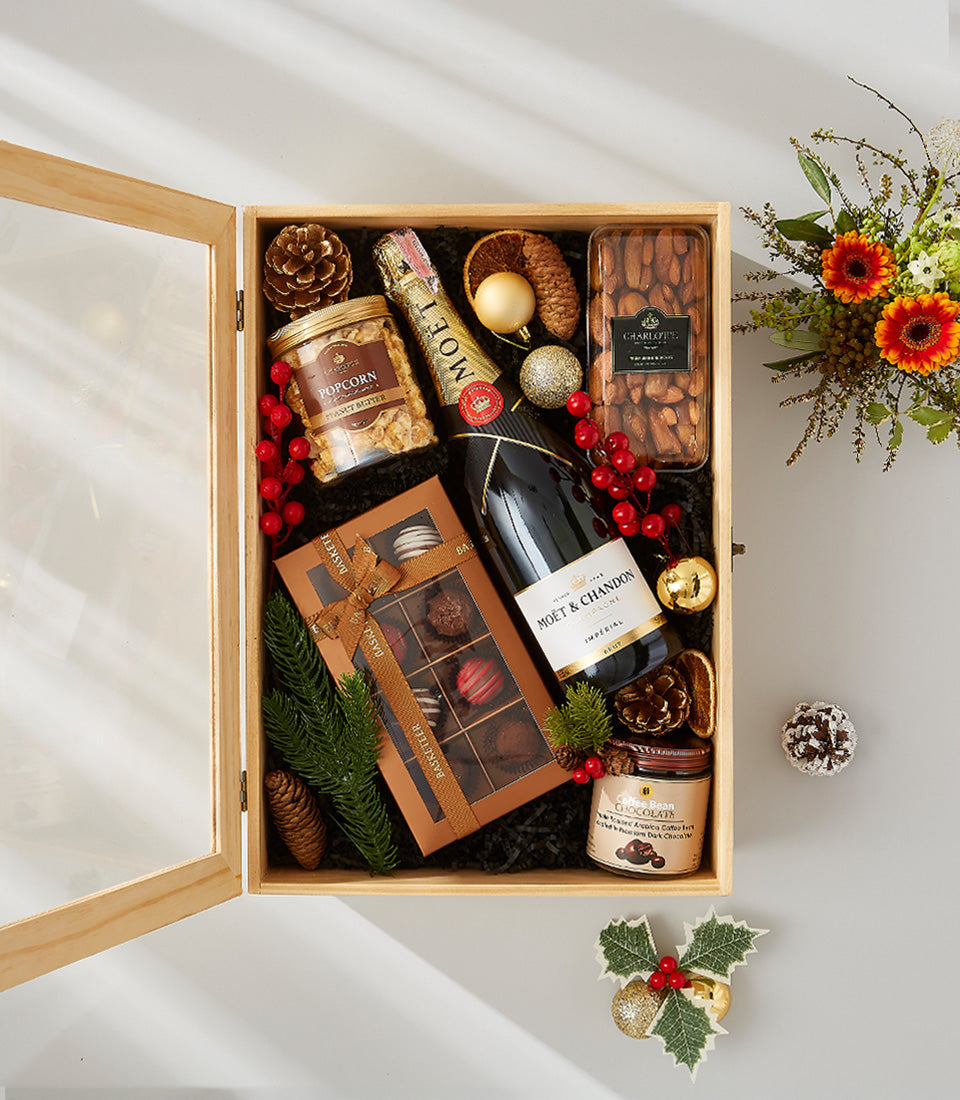 Luxury festive hamper with champagne, sparkling wine, gourmet chocolates, and holiday decorations in wooden gift box