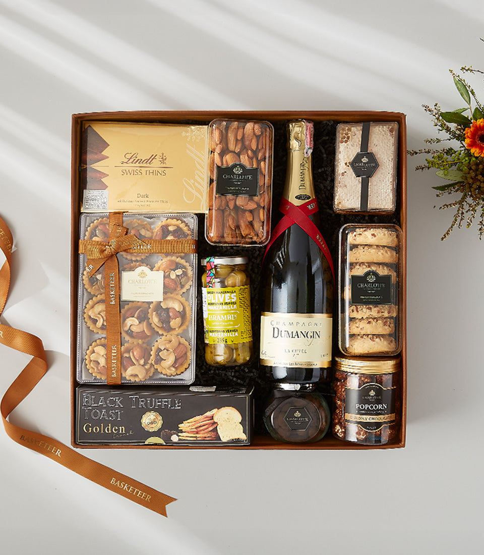 Luxury champagne gift box with gourmet chocolates, almonds, honeycomb, and truffle crackers in dark wood presentation