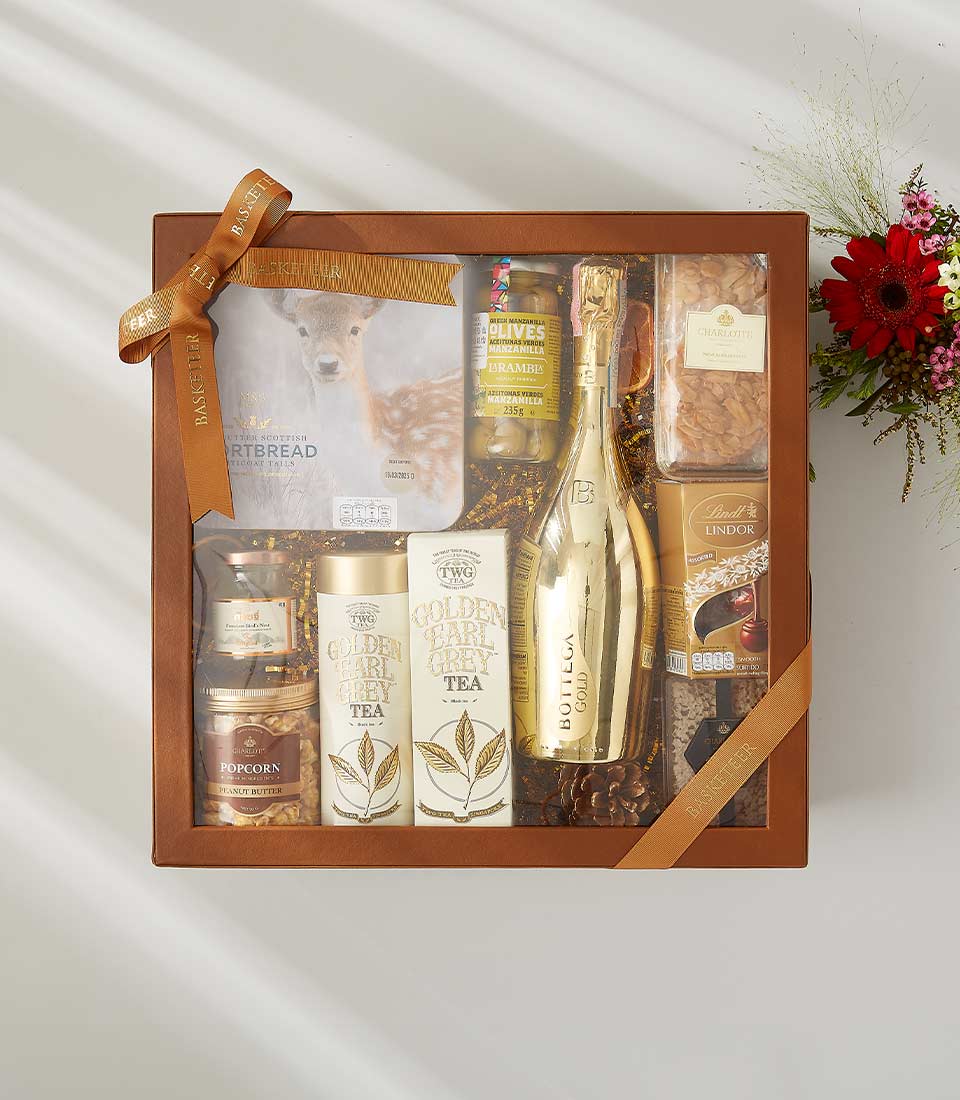 Luxury wine gift box with Bottega Gold sparkling wine, gourmet snacks, Earl Grey tea, chocolates, and fresh red gerbera