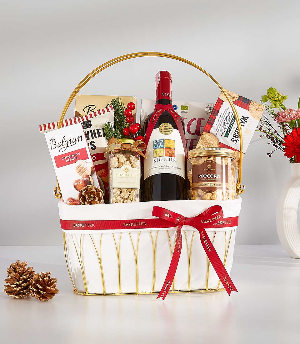 Sophisticated red wine and gourmet snacks gift hamper with gold-trimmed white basket and red ribbon bow