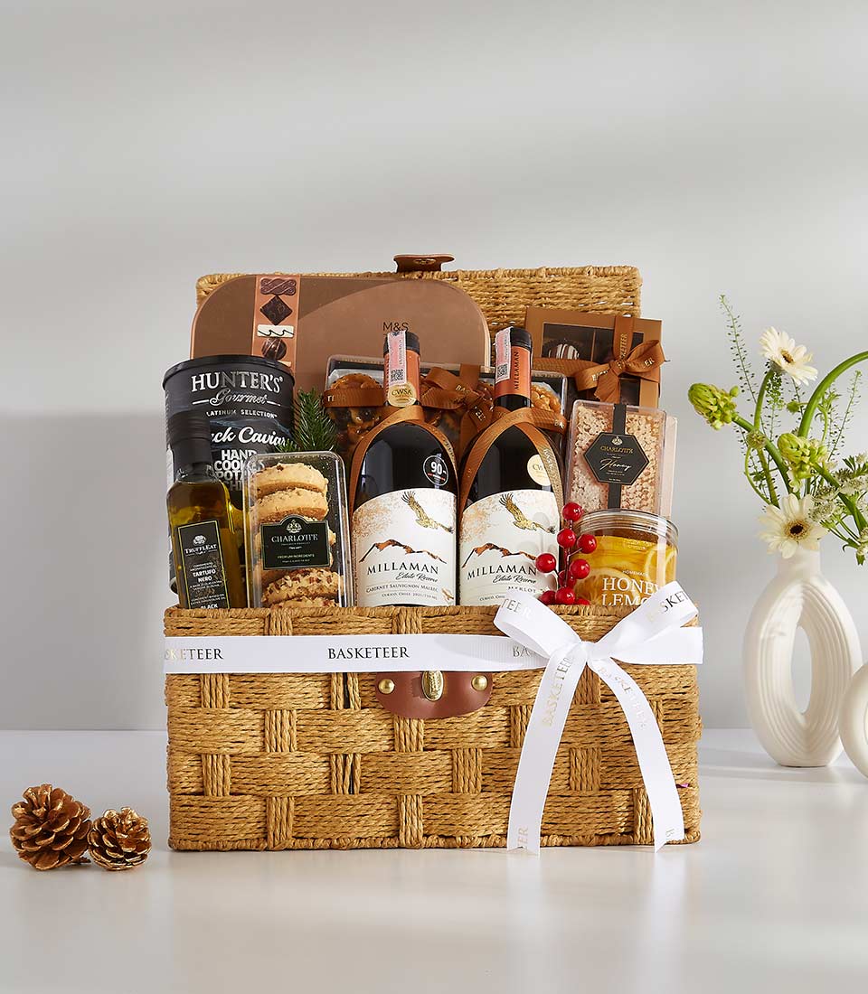 Premium woven straw hamper with red wines, gourmet foods, and white flower arrangement for luxury gifting